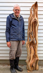 Bob standing beside a roughed out early sculpting stage of a Western red cedar sculpture, 78 tall x 17 x 14'', ~70# 