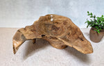 Wooden sculpture on a textured surface with a plant in the background. Top rear view of figured maple wooden irregular bowl, smooth and soft with beautiful grain patterns, intriguing clear epoxy-filled fine cracks and rich natural colors (no stains or artificial colors added).  It measures 6 tall x 23 x 16’’, 5.8 lbs. 