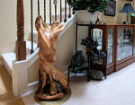 Decorative 33 inch tall wooden sculpture on a rug in a home setting with a staircase and cabinet.