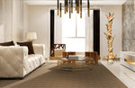 A 76 inch tall decorative, twisting and short-branched golden maroon abstract freeform tree sculpture standing in a luxury modern living room featuring a tufted cream sofa, a round gold-framed coffee table, and a textured brown rug.