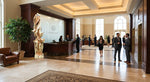 Wood sculpture 717-A1 displayed in a conference room lobby with people. One-of-a-kind 7' 3" tall by 22.5" x 22'' natural western juniper floor sculpture that emphasizes the tree's natural form and beauty. 