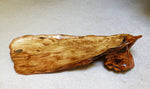Top and side view of a 34 inch long natural burl wood decorative food tray charcuterie board with a polished finish, showing rich grain patterns and organic shapes, resting on a light gray textured surface.