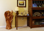 Exotic wood 32.5 inch tall freeform wood sculpture on the floor beside a home's lamp, end table, and display case.  One-of-a-kind brown and golden orange, black walnut floor sculpture with an abstract interwoven design with some parts somewhat resembling wild flowers or leaves.  It has beautiful grain patterns and measures 32.5 x 17.5 x 17'', 36.8 lbs.