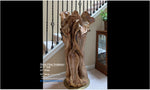 Freeform one-of-a-kind exotic maple brownish gold, wood floor sculpture standing beside a home's staircase.  The sculpture is asymmetrical with twists and turns, grooves, see through sections, and unique cup-like shapes at the top which are a bit like wildflowers.  41.5 tall x 24 wide x 16''