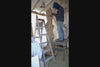 Video of artist and wood sculptor Bob Paulson standing on a work table in his shop and carving the one-of-a-kind, 7+ foot tall by 24" x 24'' natural spruce floor sculpture that is not yet completed.  When completed, it will emphasize the tree's natural form and beauty. It will have a curved and twisted shape, some live edge design and will be a combination of smooth and and a few slightly rough surfaces with beautiful rich colors and grain patterns.  